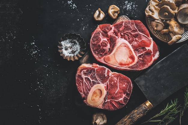 Carne cruda con verdure e spezie su sfondo scuro vintage. Vista dall'alto.