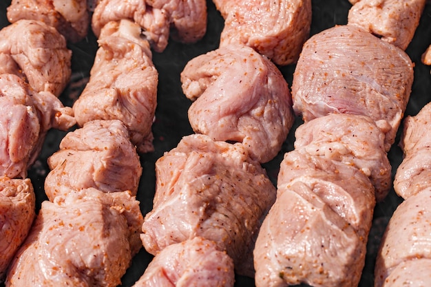 Carne cruda cotta in pezzi sul fuoco selettivo del primo piano del barbecue