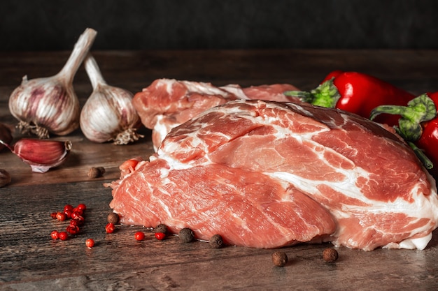 Carne Cruda Del Pezzo Di Maiale Con Le Spezie E L'aglio Sulla Tavola Di Legno