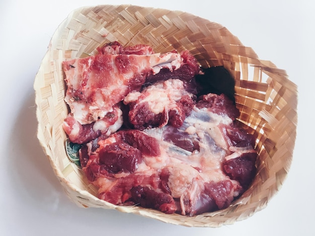 Carne cruda di agnello nel piatto di bambù o besek alla festa di Qurban durante l'Eid Al Adha Al Mubarak isolato su sfondo bianco