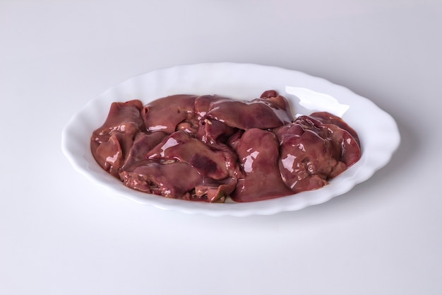 Carne cruda di fegato di pollo in un piatto su sfondo chiaro