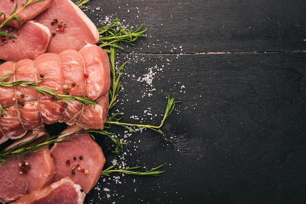 Carne cruda Filetto di manzo con rosmarino e spezie su fondo di legno nero Vista dall'alto Spazio libero per il testo