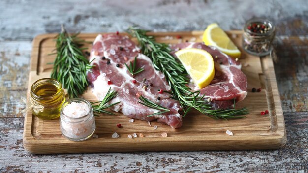 Carne cruda fresca con rosmarino e spezie su una tavola di legno