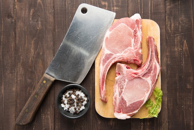 Carne cruda fresca sul tagliere e mannaia sulla tavola di legno.