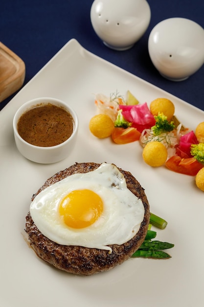 Carne d'uovo di manzo sul piatto bianco sulla tovaglia blu nel ristorante