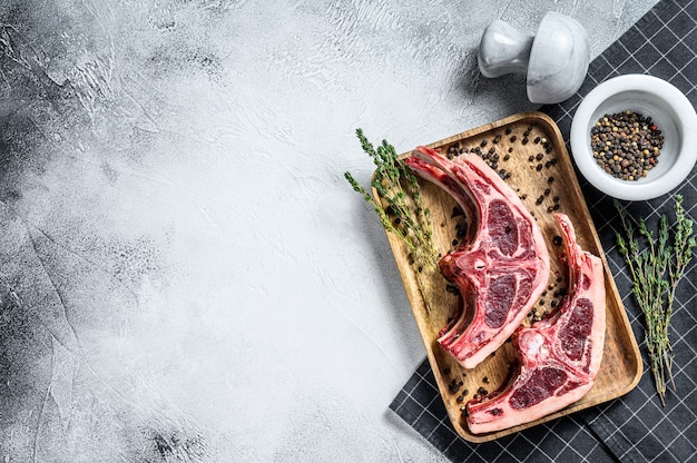 Carne di agnello cruda sulle costole con rosmarino e spezie. Sfondo grigio. Vista dall'alto. Copia spazio