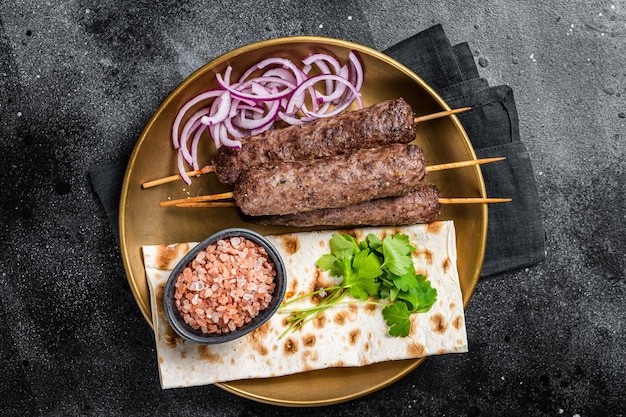 Carne di agnello kofta kebab cipolla e pane piatto su piastra Sfondo nero Vista dall'alto