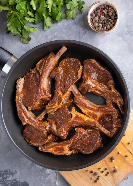 Carne di agnello marinata cruda su una padella. Carne pronta da cuocere. Vista dall'alto