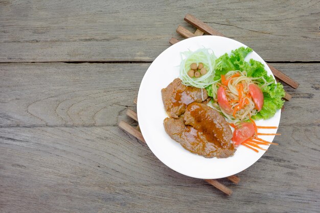 Carne di bistecca alla griglia con insalata di verdure su fondo di legno