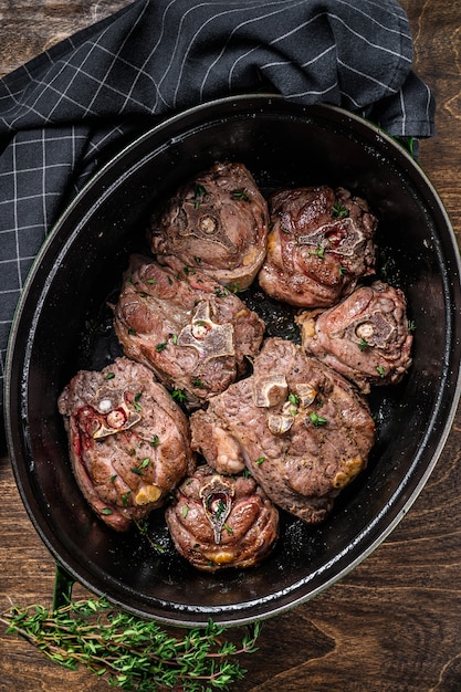 Carne di collo di agnello stufata in padella con erbe aromatiche. fondo in legno. Vista dall'alto.