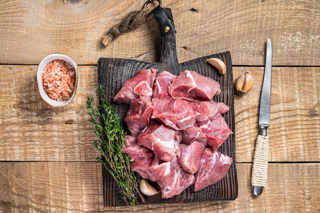 Carne di cuccioli di maiale a dadini cruda fresca con spezie su una tavola di legno del macellaio. tavolo di legno. Vista dall'alto.