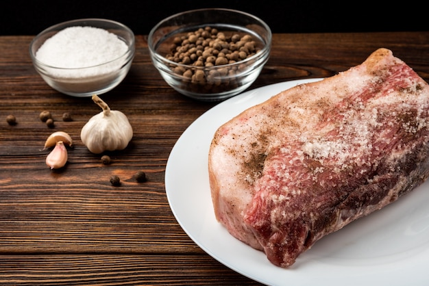 Carne di maiale con spezie su legno scuro.