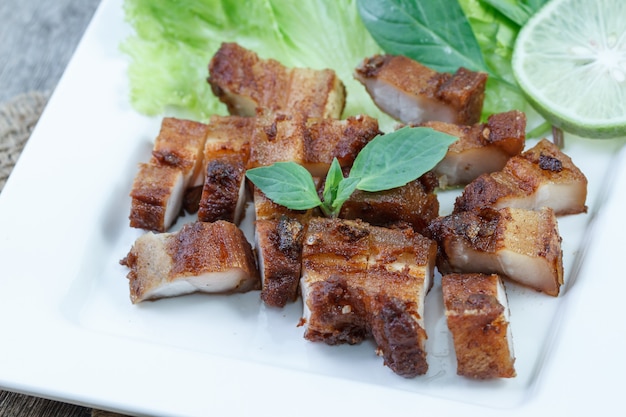 Carne di maiale croccante con aglio e pepe sul piatto bianco