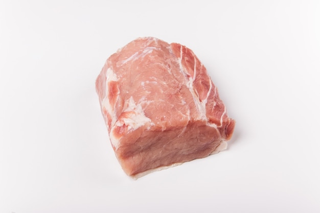 Carne di maiale cruda su sfondo bianco. Intero pezzo di carne. Vista piana laico e dall'alto