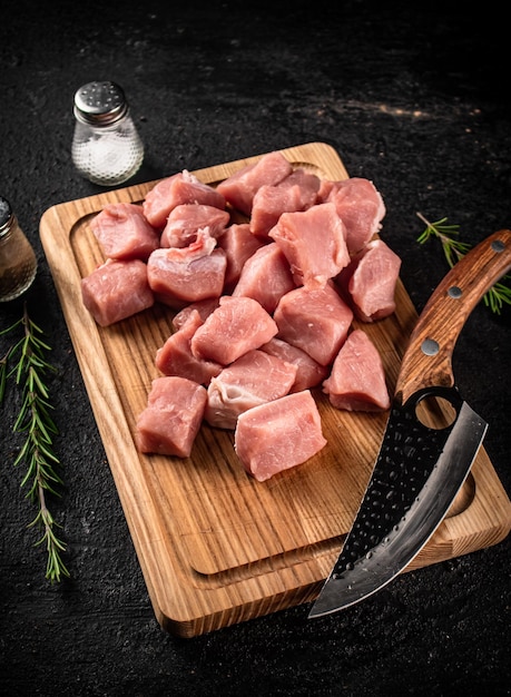 Carne di maiale cruda tritata su un tagliere con spezie al coltello e rosmarino