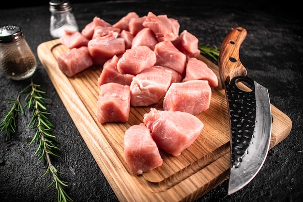 Carne di maiale cruda tritata su un tagliere con spezie al coltello e rosmarino