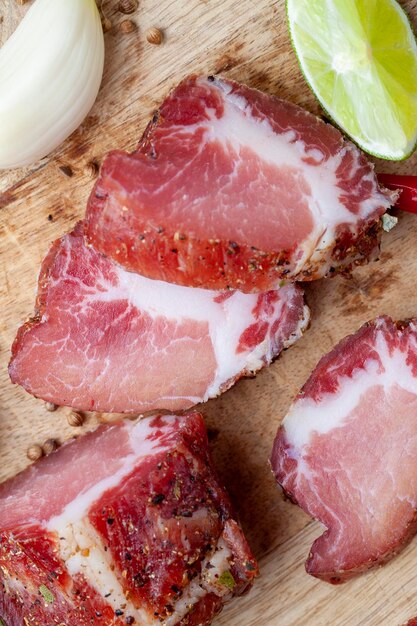 Carne di maiale e pancetta affettate durante la cottura Carne secca tagliata a pezzi su un tagliere