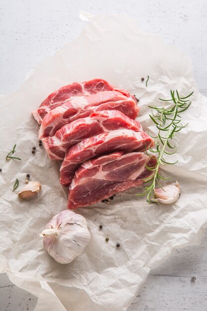 Carne di maiale. Fette di maiale con aglio pepe e rosmarino su sfondo bianco conkrete.