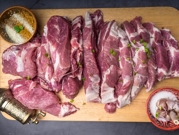 Carne di maiale fresca con ingredienti per cucinare su sfondo scuro