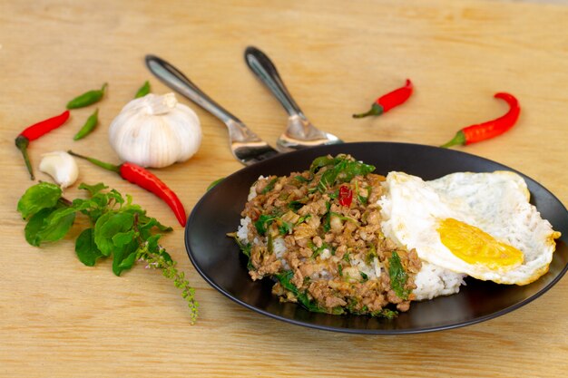 Carne di maiale salata con peperoncino e foglie di basilico in lamiera nera sul tavolo di legno