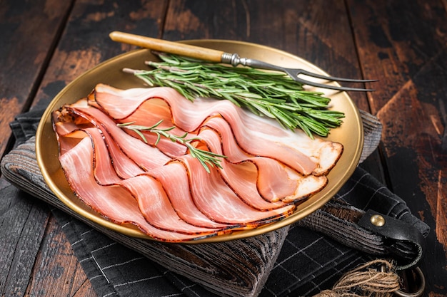 Carne di maiale stagionata Prosciutto della Foresta Nera Pancetta con rosmarino Fondo in legno Vista dall'alto