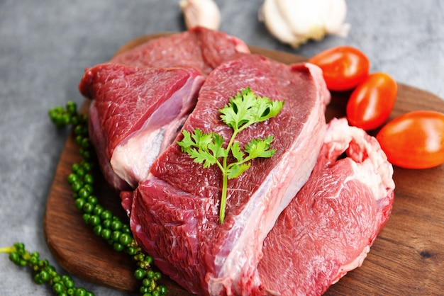 Carne di manzo cruda sul tagliere di legno sul tavolo della cucina per cucinare bistecca di manzo arrostita o grigliata con ingredienti erbe e spezie Proteine animali di manzo fresche