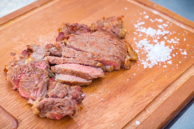 Carne di manzo deliziosamente affettata alla griglia media adagiata su un tagliere di legno salato