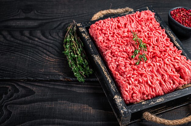 Carne di manzo e maiale macinata cruda in un vassoio di legno con erbe aromatiche