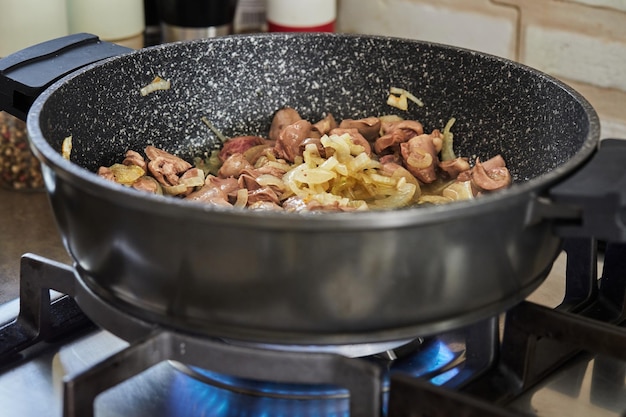 Carne di manzo fritta con cipolle in padella su fornello a gas