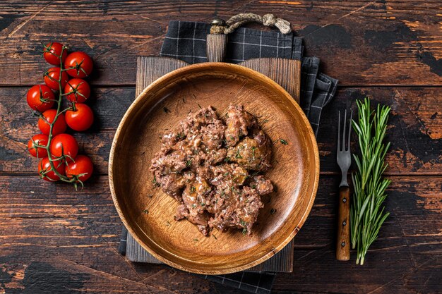 Carne di manzo stufata in un piatto di legno Sfondo di legno scuro Vista dall'alto