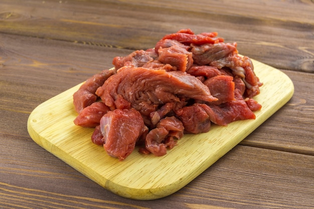 Carne di manzo tagliata a pezzi bugie su una tavola di legno