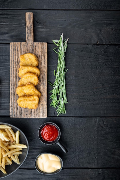 Carne di pepite di pollo croccanti fritte su fondo di legno nero, vista dall'alto, con spazio per il testo.