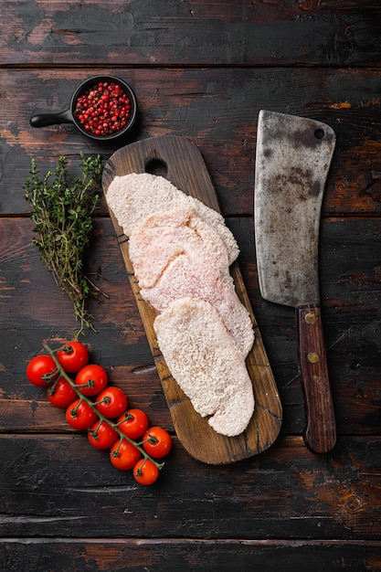 Carne di pollo cotoletta cruda impostata su un vecchio tavolo in legno scuro sfondo vista dall'alto piatto con spazio per la copia del testo