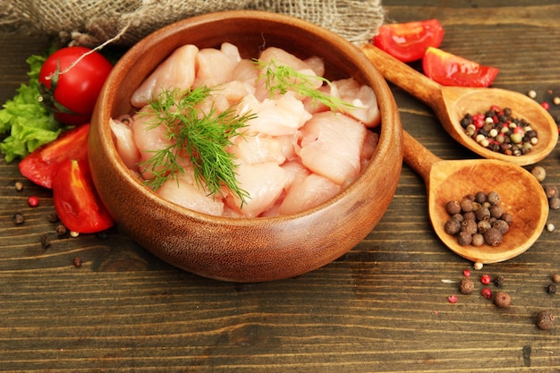 Carne di pollo cruda in ciotola su fondo di legno