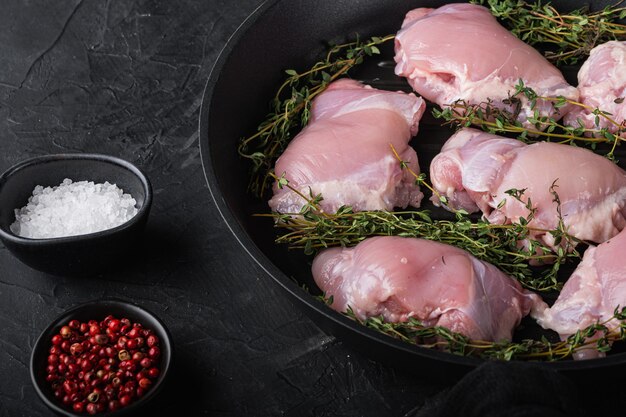 Carne di pollo cruda sulla padella per grigliare su sfondo nero.