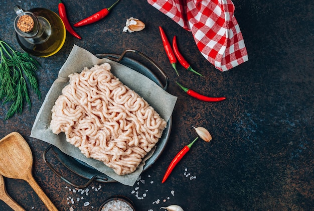 Carne di pollo macinata cruda in piatto su sfondo grigio Carne macinata con ingredienti per cucinare Vista dall'alto