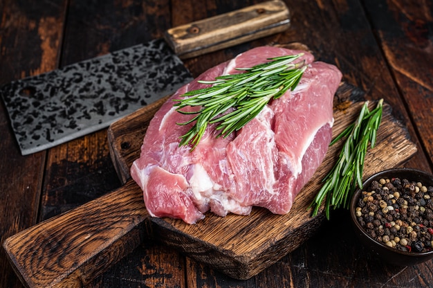 Carne di spalla di maiale cruda fresca tagliata con ingredienti e spezie sul tavolo della cucina. Tavolo in legno scuro. Vista dall'alto.