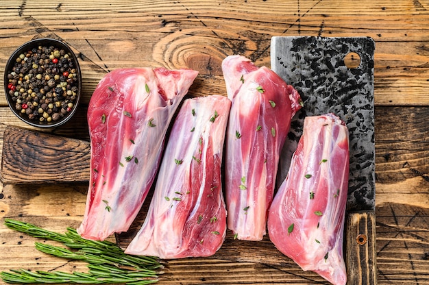 Carne di stinchi di agnello crudo fresco con erbe e pepe. tavolo di legno. Vista dall'alto.