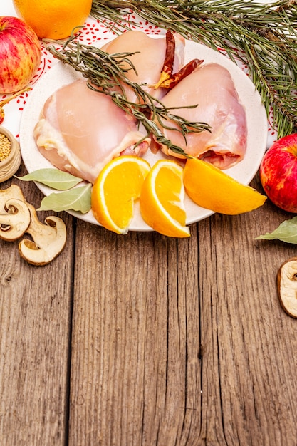 Carne disossata di pollo crudo con erbe e frutti sul piatto. Cucinare al Giorno del Ringraziamento