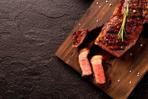 Carne fresca alla griglia. Bistecca di manzo alla griglia mediamente cotta su tavola di legno. Vista dall'alto.