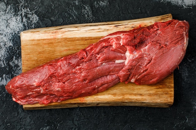 Carne fresca cruda, bistecca di manzo su sfondo nero, vista dall'alto.