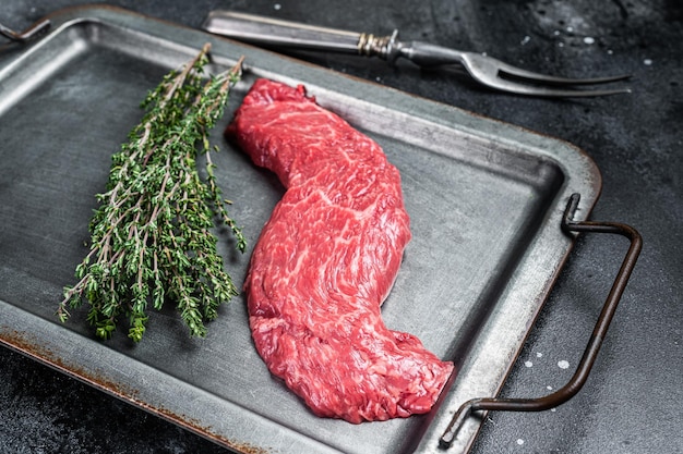 Carne fresca cruda Bistecca Machete gonna con timo su vassoio in acciaio Sfondo nero Vista dall'alto