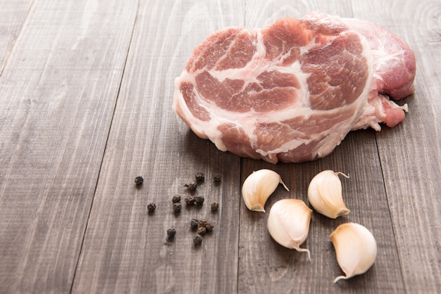 Carne fresca cruda ed aglio, pepe su fondo di legno