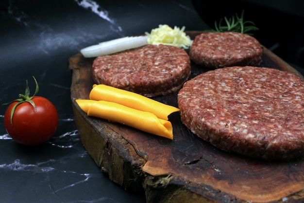 Carne fresca e cruda di hamburger Hamburger crudi su tavola da taglio con sfondo di legno