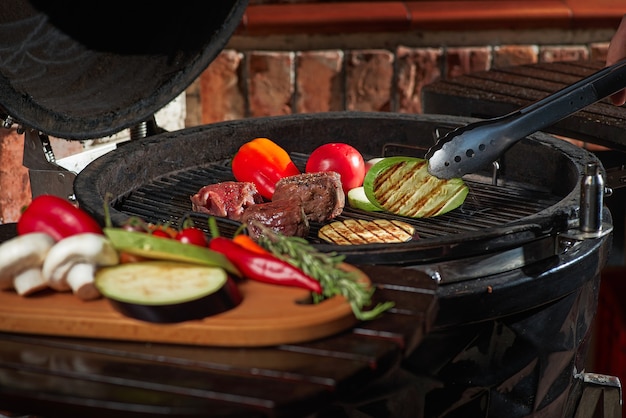 Carne fresca e verdure grigliate in un barbecue casalingo del fine settimana. Concetto di cucina, cucina scura.