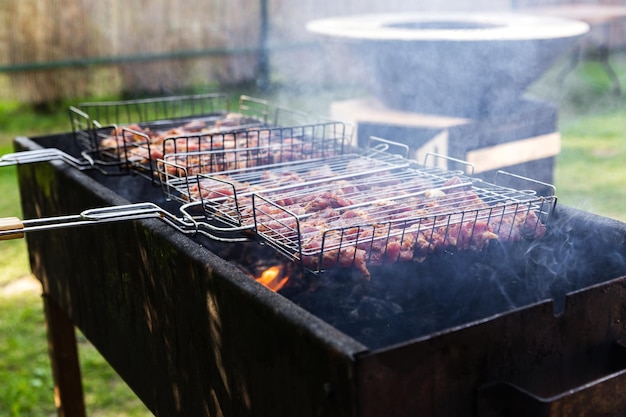 Carne fresca per barbecue fritta sul fuoco Messa a fuoco selettiva Carne di maiale alla griglia Cucinare barbecue alla griglia con fumo Picnic in natura Cibo sano e corretta alimentazione