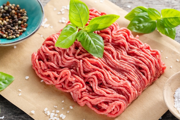 Carne macinata con spezie su carta sul tavolo. Avvicinamento