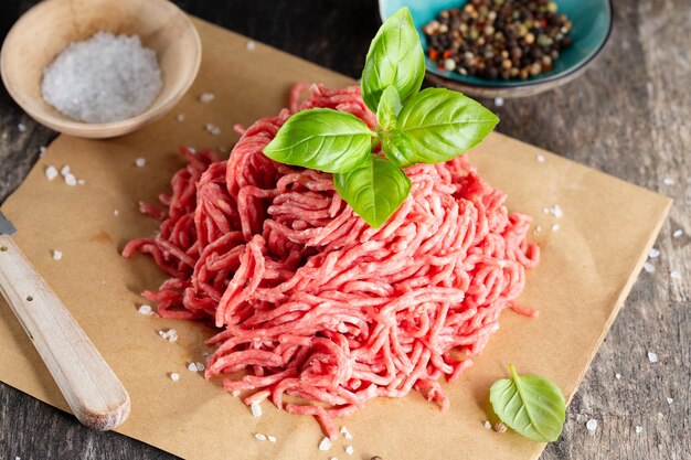 Carne macinata con spezie su carta sul tavolo. Avvicinamento