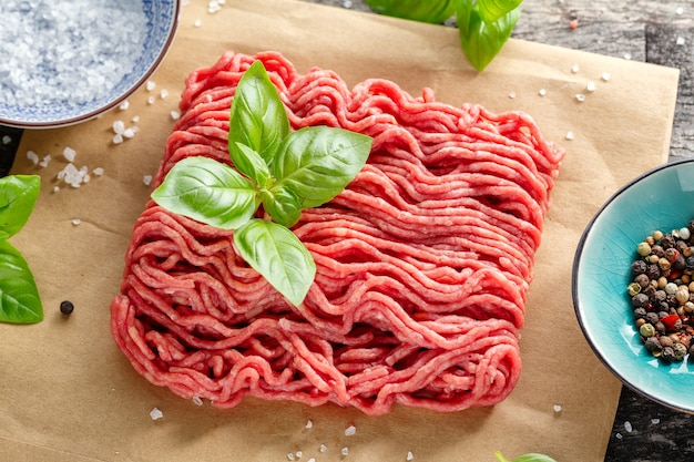 Carne macinata con spezie su carta sul tavolo. Avvicinamento