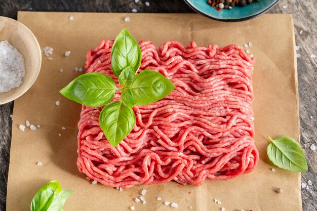 Carne macinata con spezie su carta sul tavolo. Avvicinamento